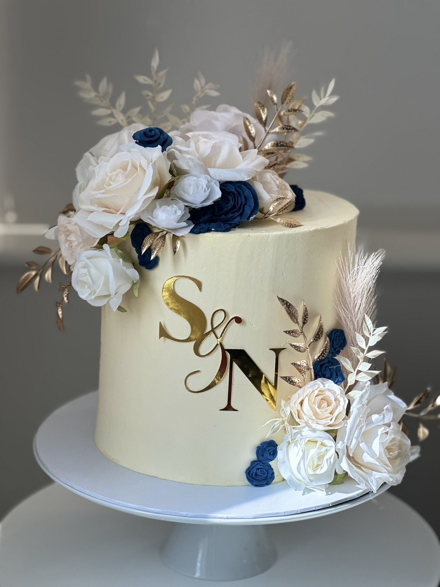 Wedding cake with gold initials S&N and blue roses