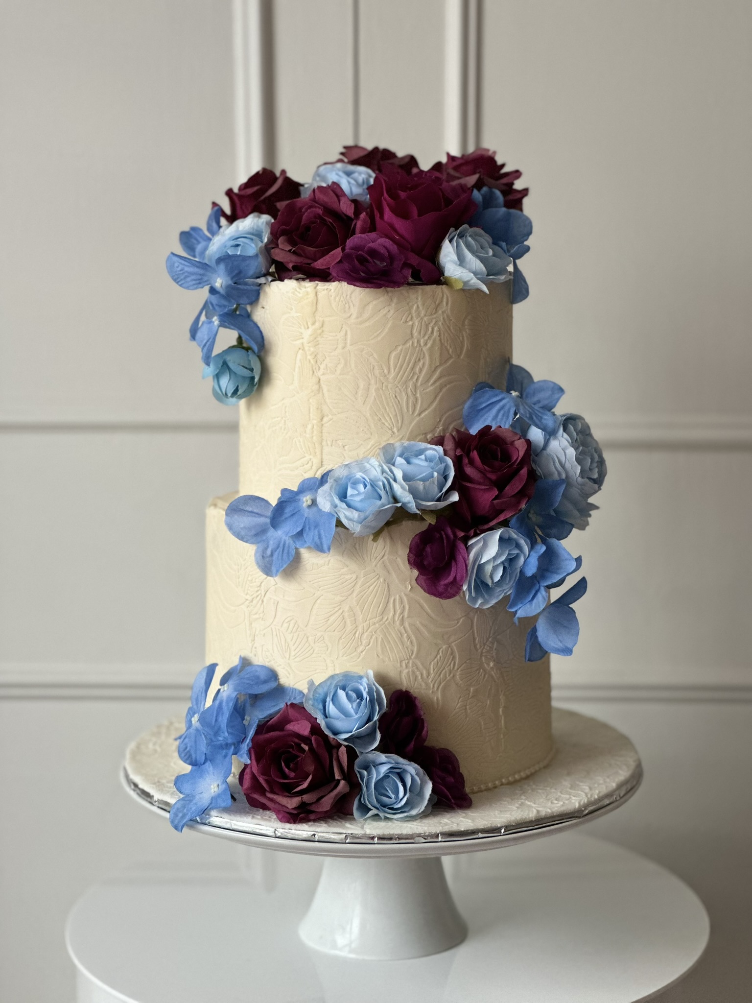 2 tier ivory wedding cake with blue and burgundy flowers