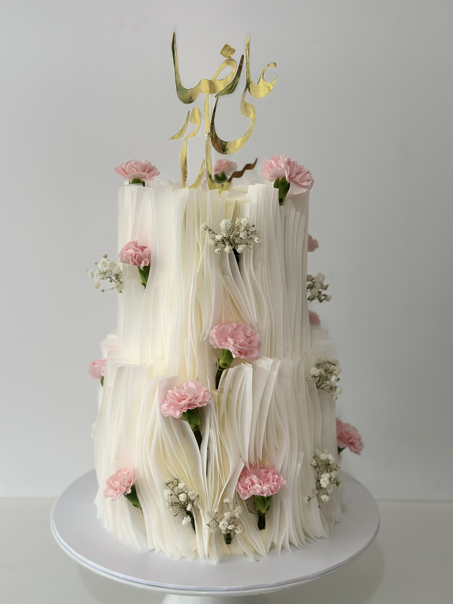 2 tier white ruffled wedding cake with pink carnations